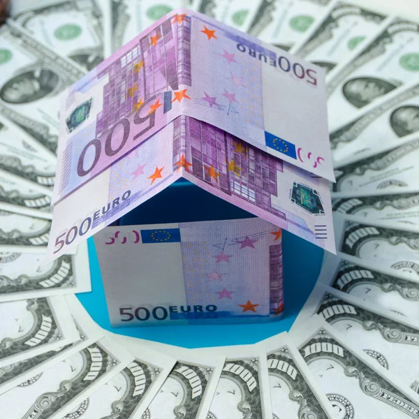 Casa hecha de billetes en euros, en un círculo dólar — Foto de Stock