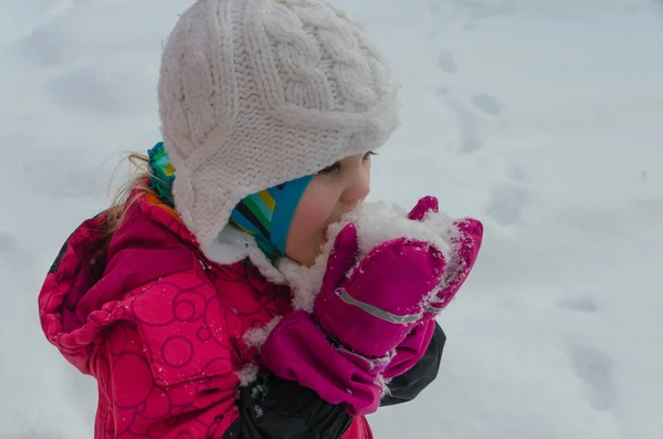 O inverno na rua, criança comendo neve — Fotografia de Stock