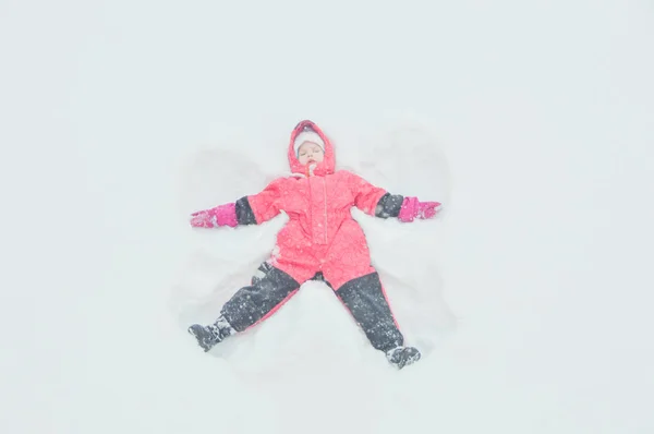 En flicka att göra ängel i snön — Stockfoto