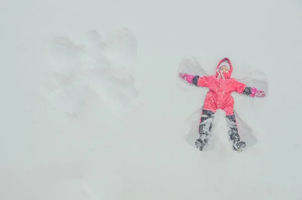 Ein Mädchen, ein Kind macht einen Engel im Schnee — Stockfoto