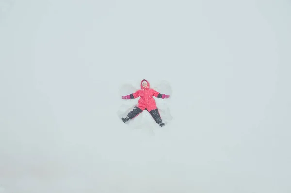 Menina fazendo anjo na neve — Fotografia de Stock