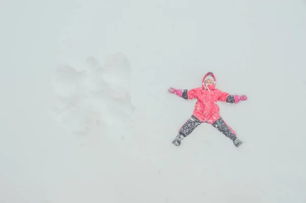 Το κορίτσι, ένα παιδί κάνει έναν άγγελο στο χιόνι — Φωτογραφία Αρχείου