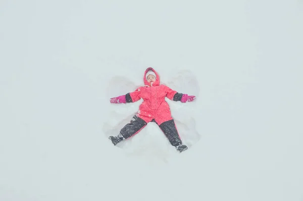 A menina fazendo anjo na neve — Fotografia de Stock