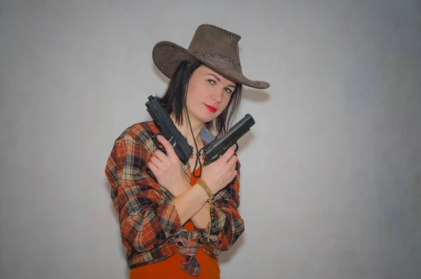 Cowboy flicka som innehar två pistoler, kors på korset, på grå backgro — Stockfoto