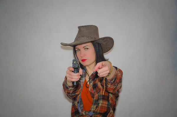 Ковбой девушка с пистолетом палец жестом вас, на сером фоне — стоковое фото