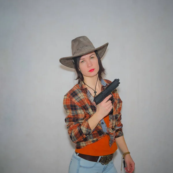 Девушка ковбой с пистолетом на сером фоне — стоковое фото