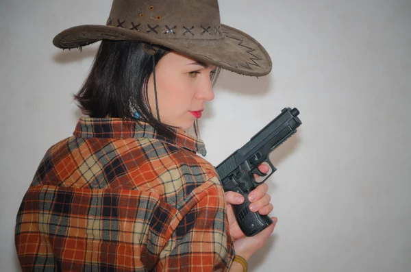 Sur un fond gris, la fille le cow-boy avec le pistolet, debout — Photo