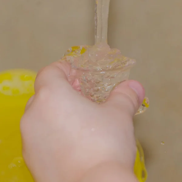 El niño recoge el agua en una taza pequeña — Foto de Stock