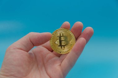 cryptocurrency bitcoin altın, mavi arka plan üzerinde elinde