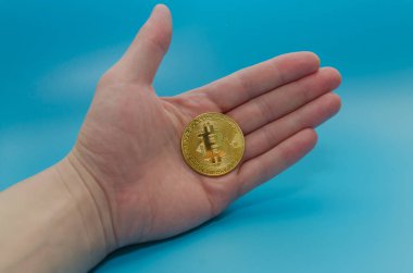 cryptocurrency bitcoin altın, mavi arka plan üzerinde elinde