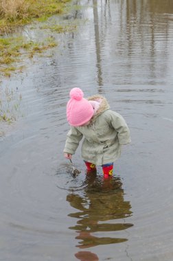 Kız, erken Bahar ayakta büyük bir çocuk kauçuk botlar 