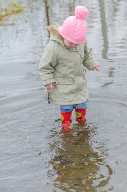 Kız, erken Bahar ayakta büyük bir çocuk kauçuk botlar 
