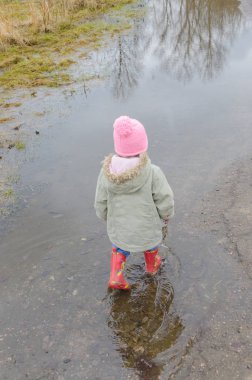 Kız, erken Bahar ayakta büyük bir çocuk kauçuk botlar 