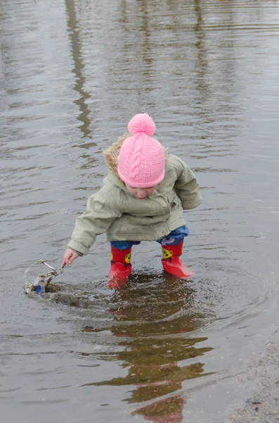Kız, erken Bahar ayakta büyük bir çocuk kauçuk botlar 