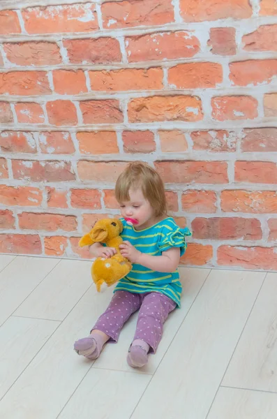 Een meisje, een kind met een fopspeen en herten in handen op achtergrond — Stockfoto