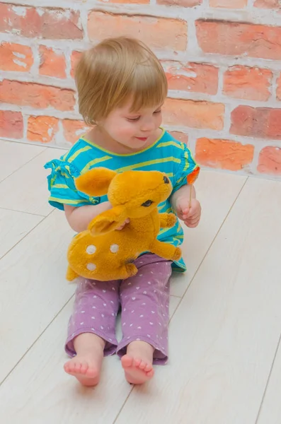 Een klein meisje, een kind met een lolly en een hert speelgoed — Stockfoto