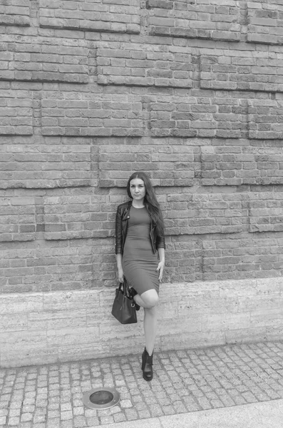 Дівчина в сукні та шкіряній куртці на фоні цегляної стіни — стокове фото