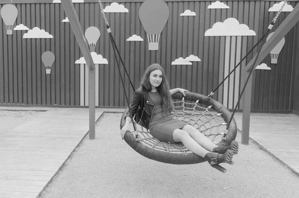 Девочка на детской площадке качается на качелях — стоковое фото