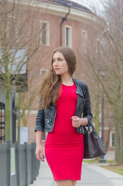 La chica en el vestido y una chaqueta de cuero con un bolso en su han —  Fotos de Stock