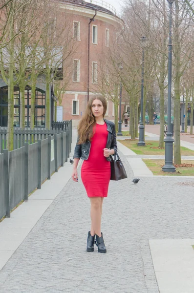 Het meisje in de jurk en een leren jas met een zak in haar han — Stockfoto