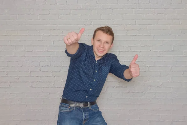 Man in een shirt gebaren naar de muur van witte baksteen een plaats voor een — Stockfoto