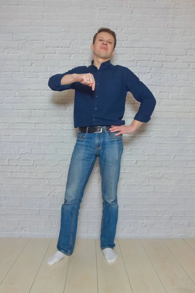 Muž ukazuje gesto před bílou cihlovou zdí — Stock fotografie