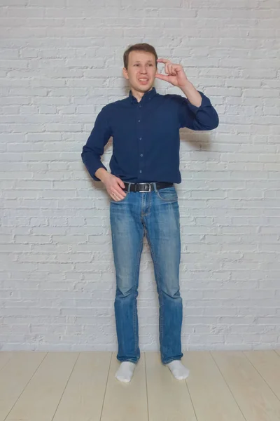 Чоловік показує жест перед білою цегляною стіною — стокове фото