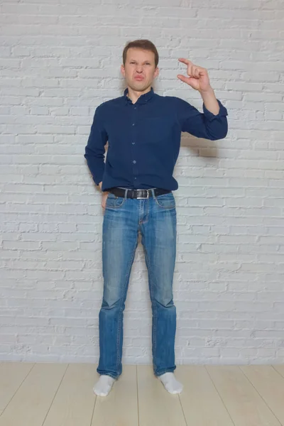Мужчина показывает жест перед стеной из белых брик — стоковое фото