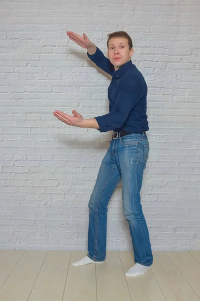 Muž ukazuje gesto před bílou cihlovou zdí — Stock fotografie