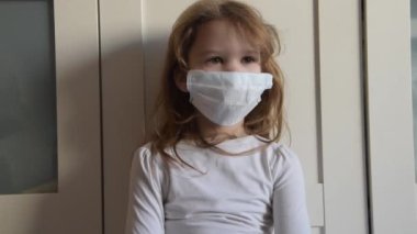 Tıbbi maskeli bir çocuk bir virüsten gelen antiseptik spreyle ilgilenir.