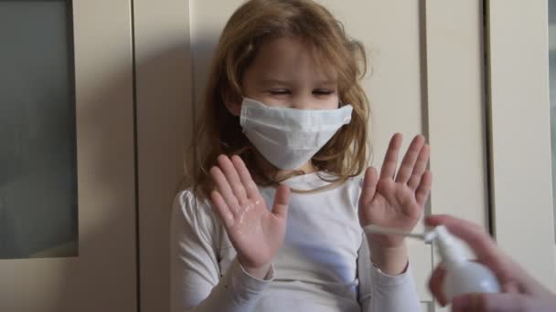 Ребенок в медицинской маске обрабатывает антисептический спрей от вируса — стоковое видео