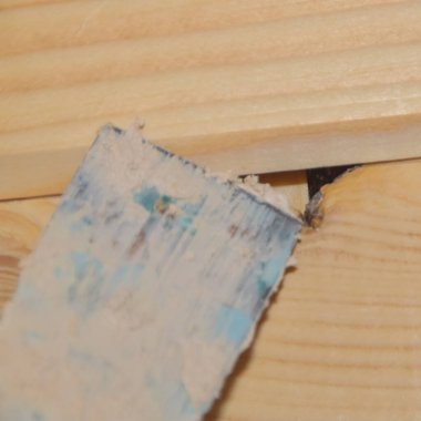 İşçi, ahşap bir duvardaki deliğe macun koyar.