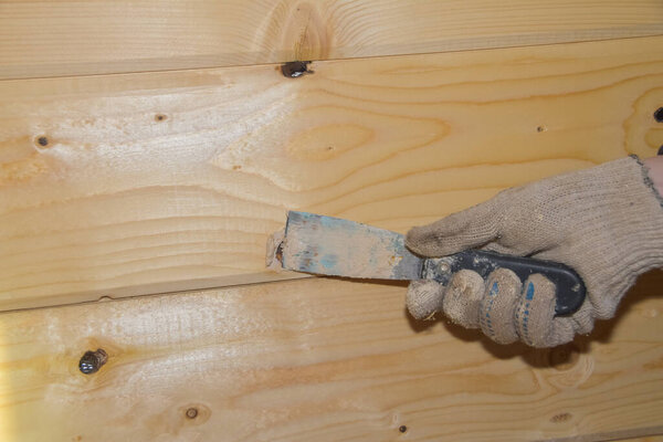 the worker puts putty on a hole in a wooden wall