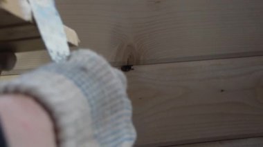 İşçi, ahşap bir duvardaki deliğe macun koyar.