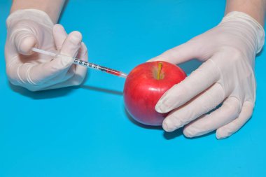 Mavi arka planda Apple 'da çekilen kimyasallarla dolu şırınga.