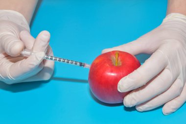 Mavi arka planda Apple 'da çekilen kimyasallarla dolu şırınga.