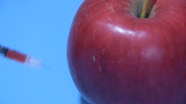 Spritze mit Chemikalien im Apple vor blauem Hintergrund — Stockvideo