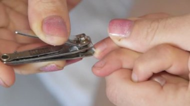 Bir anne bebek tırnaklarını kesiyor.