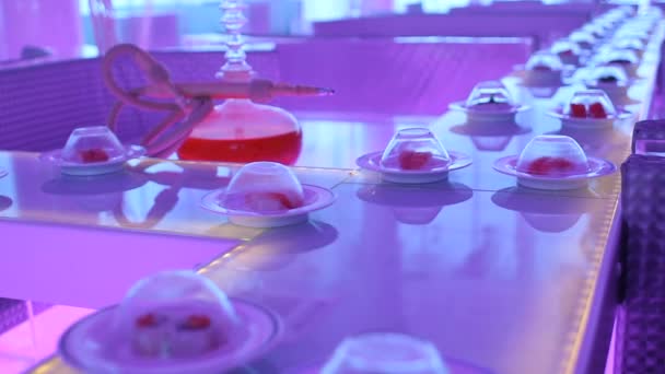 Plates with different sushi go around the conveyor belt in neon light. — Stock Video