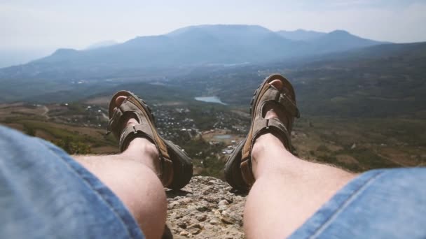 Hombres piernas en los zapatos marrones que yacen en las rocas en el fondo de la montaña — Vídeos de Stock