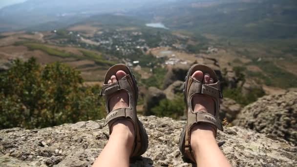 Hombres piernas en los zapatos marrones que yacen en las rocas en el fondo de la montaña — Vídeos de Stock