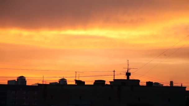 Západ slunce v městě. Nadýchané barevné mraky nad černými obrysy budov. Krásné cloudscape. — Stock video