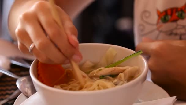 Mujer revolviendo la sopa de fideos chiken vietnamita pho ga con palillos asiáticos. Comida tradicional en Asia. Camboya . — Vídeos de Stock