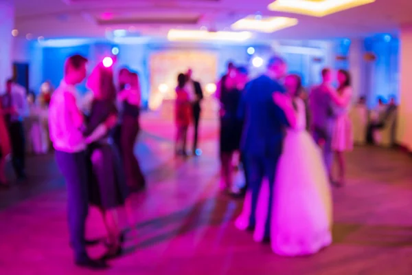 Wedding. Dancing bride and groom, couples and guests. Blurred background.