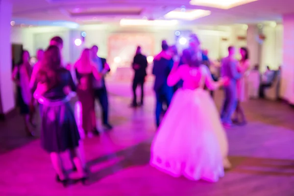 Wedding. Dancing bride and groom, couples and guests. Blurred background.