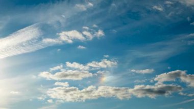 Zaman atlamalı küçük mavi gökyüzü üzerinde beyaz kabarık bulutlar. Gökkuşağı ile güzel cennet