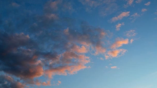 Idő telik klip rózsaszín bolyhos felhők, kék ég alatt. A naplemente gyönyörű cloudscape — Stock videók