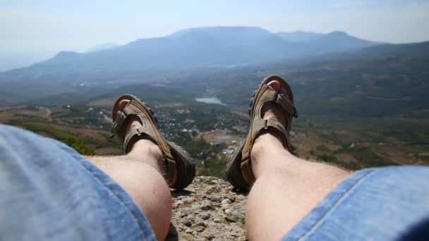 Hombres piernas en los zapatos marrones que yacen en las rocas en el fondo de la montaña — Vídeos de Stock