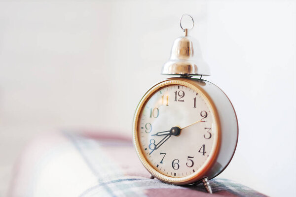 Old fashioned alarm clock on plaid tartan background.