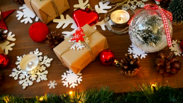 Kerstmis en Nieuwjaar achtergrond met cadeautjes, verlichting, kaarsen en andere decoraties. Gift in Kraft papier met red fir tree. — Stockvideo